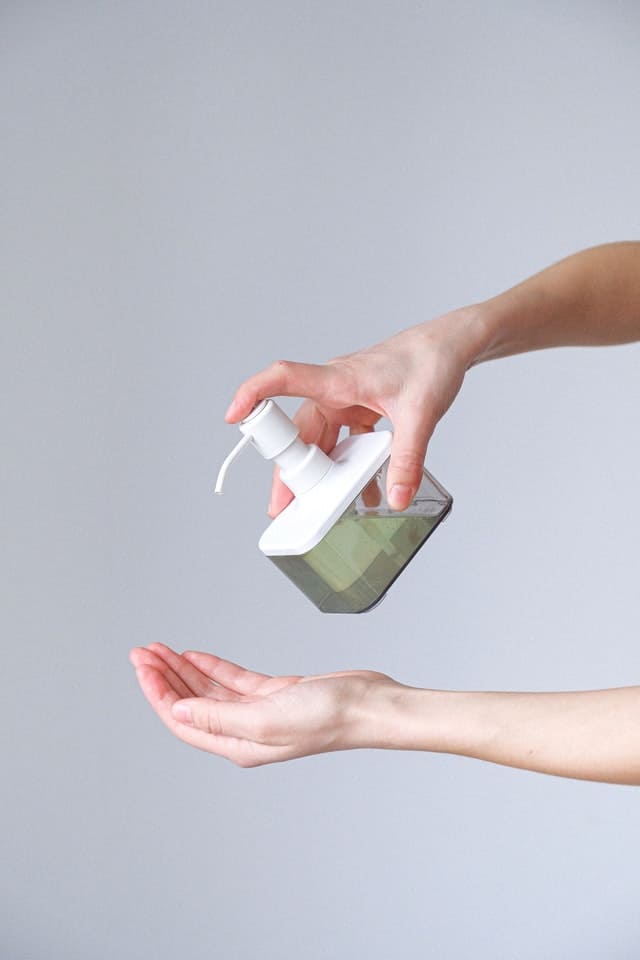 A person pouring liquid soap on their hand to prevent being the cause of infections in their household.