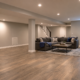 Finished basement renovation with lounge seating, egress-style window, recessed lights, and durable flooring