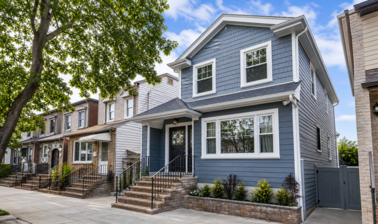 Finished Queens home exterior with blue-gray siding white trim and masonry stoop